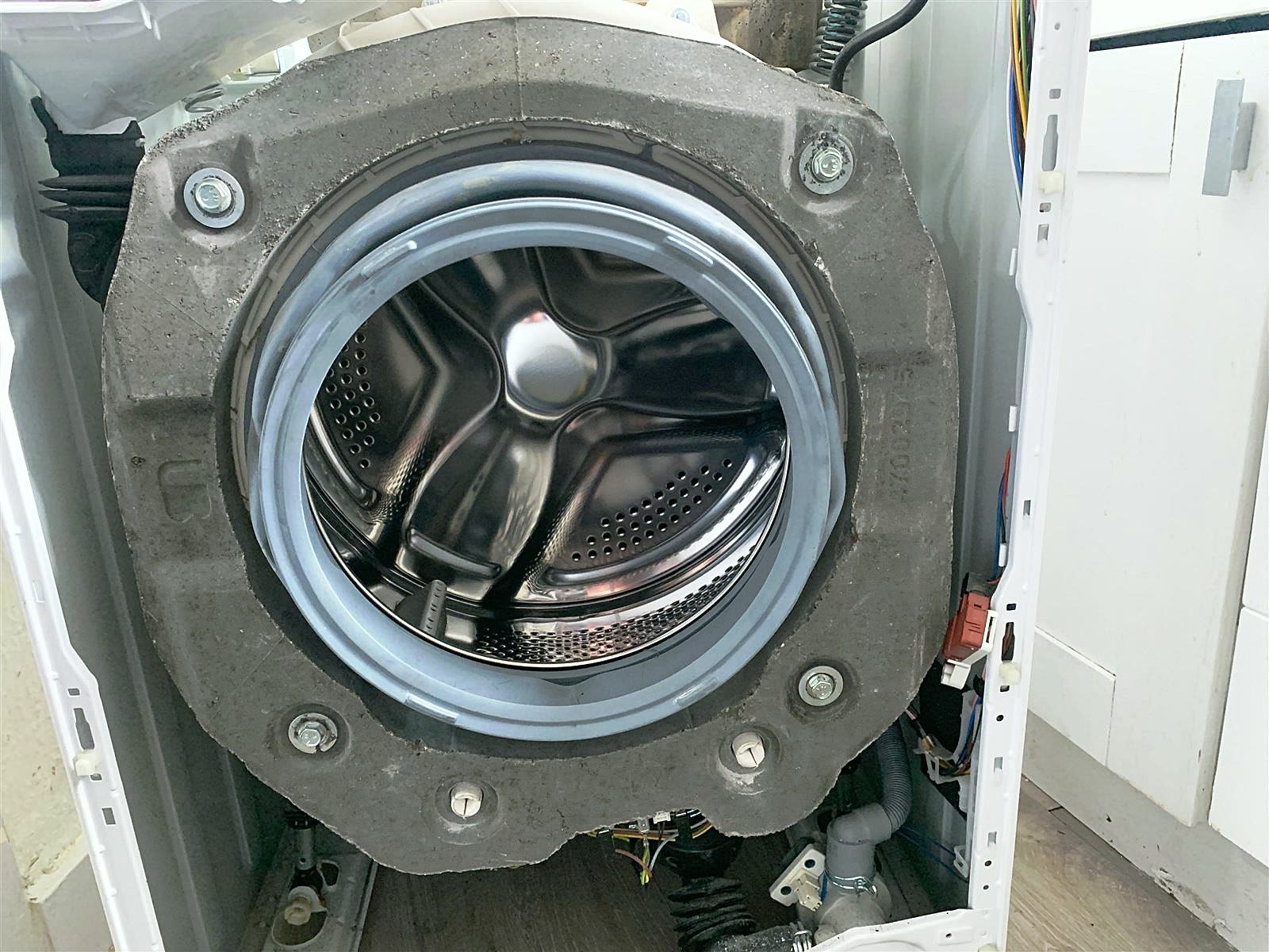 Washing machine with the front panel removed, drum and door seal exposed for repair